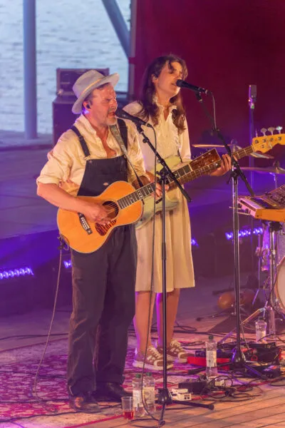 Musiikkiesitys, jossa mies soittaa kitaraa ja laulaa, ja nainen esiintyy sähköinstrumentin kanssa.