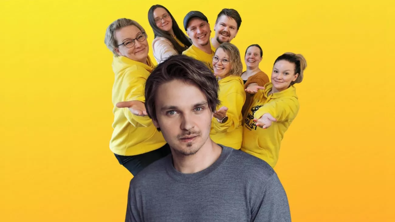 Mies harmaassa paidassa etualalla ja seitsemän henkilöä keltaisissa huppareissa taustalla iloisesti poseeraamassa.