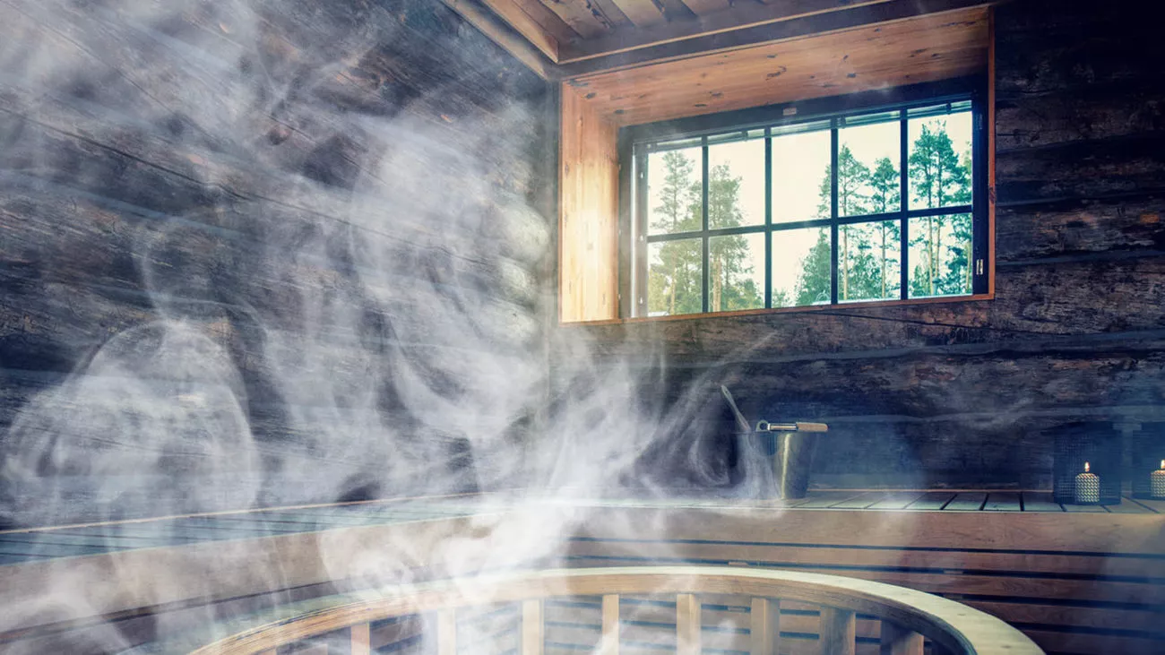 Savuisa sauna sisätiloissa, jossa on puupinnat ja ikkuna metsänäkymällä.
